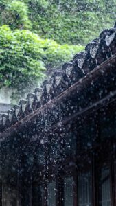 Rain falls over a traditional Chinese roof, capturing the essence of summer showers.