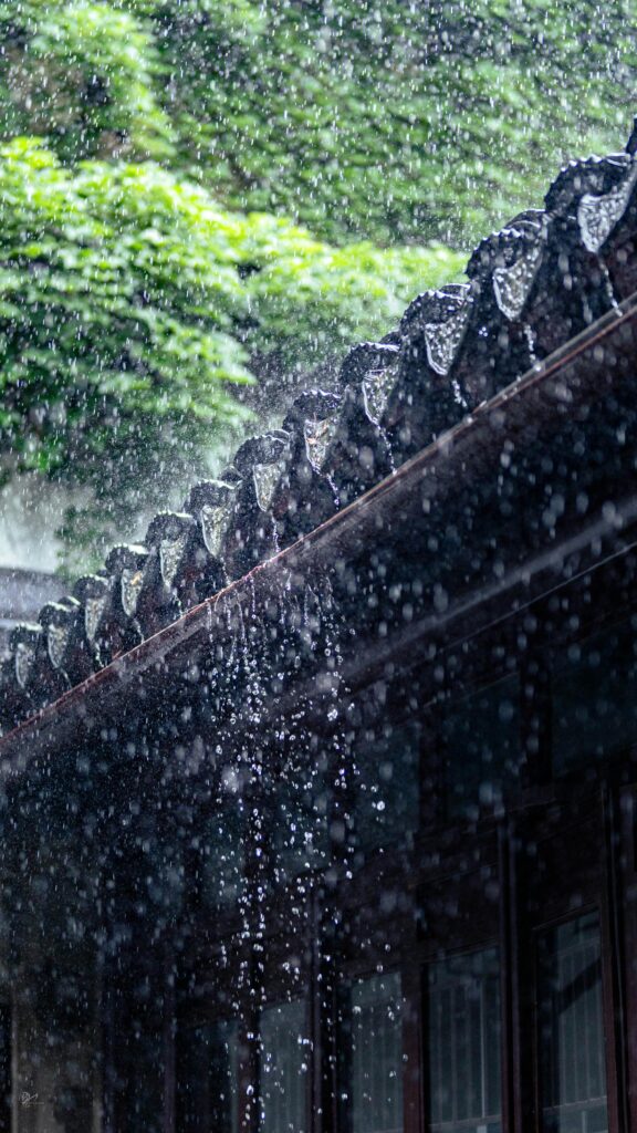 Rain falls over a traditional Chinese roof, capturing the essence of summer showers.